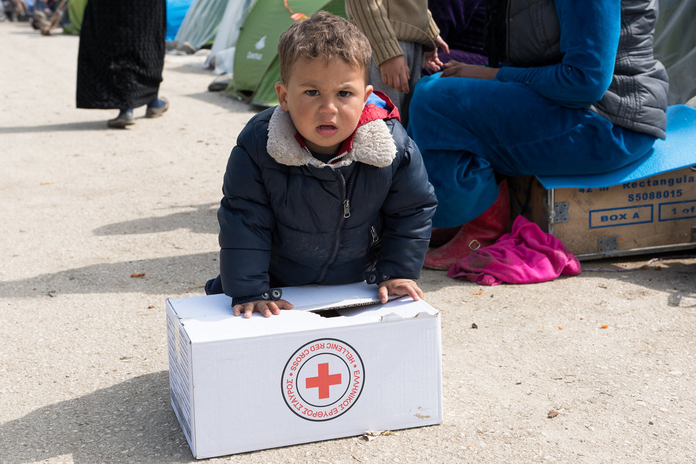 A little boy tries to carry a box with supplies given from the Greek Red Cross on March 17, 2015 in the refugees camp of Eidomeni.